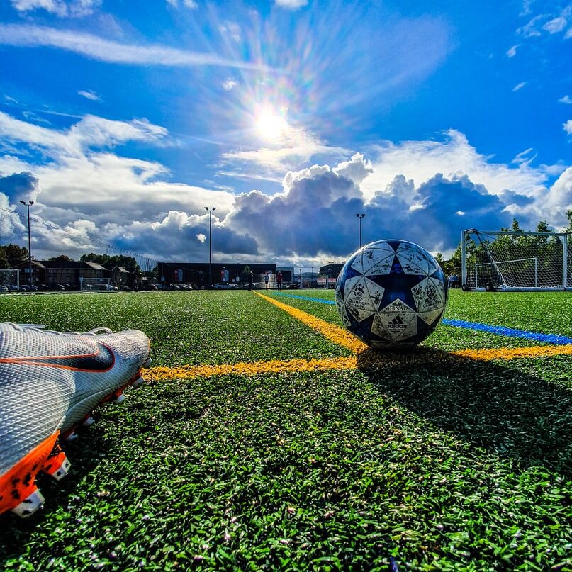 blue and grey soccer ball on green field under white and blue sky during daytime