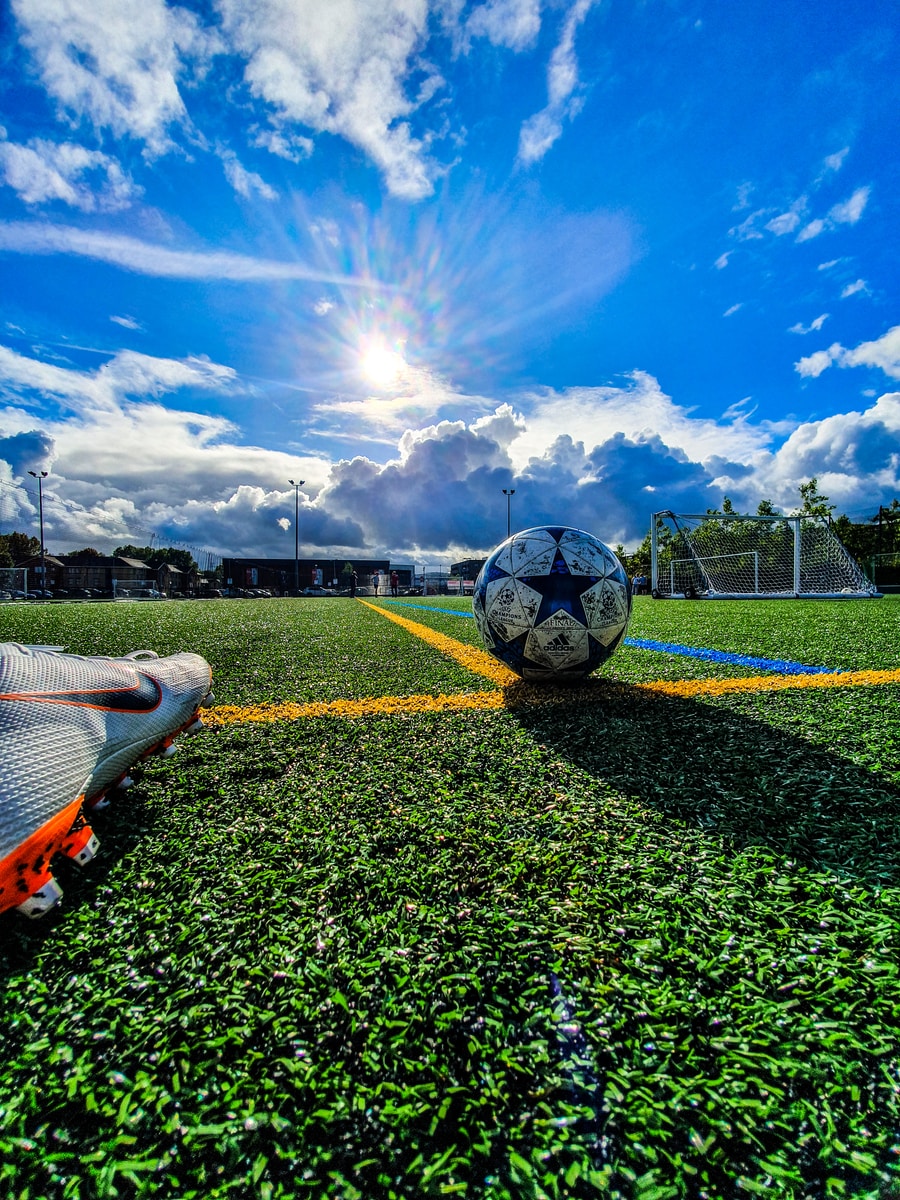 blue and grey soccer ball on green field under white and blue sky during daytime